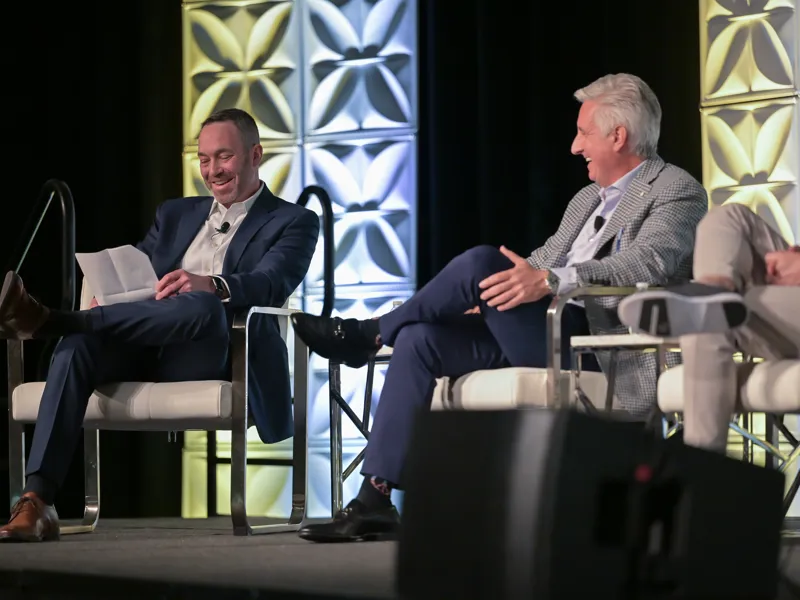 Two business people talking on stage at a conference.