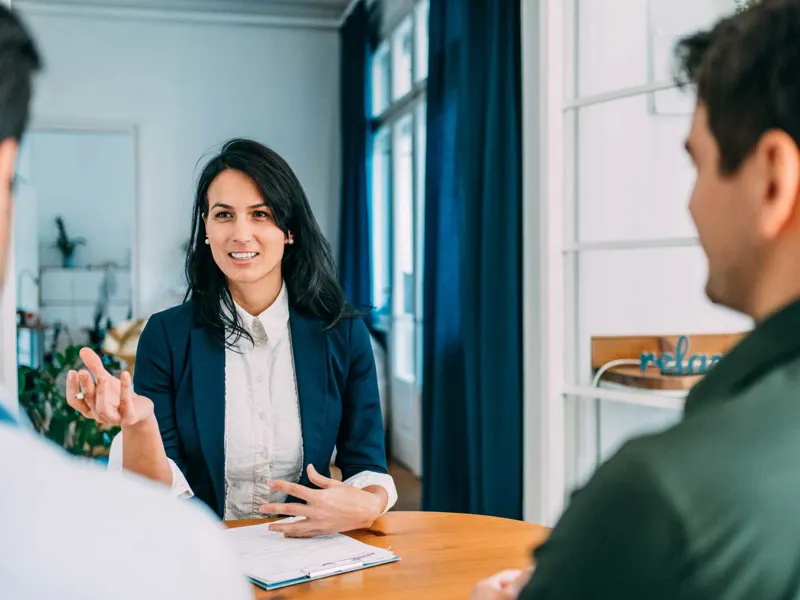 Woman advising clients at a table.